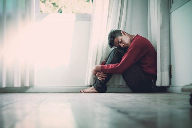 Person struggling with mental health huddles in corner of room